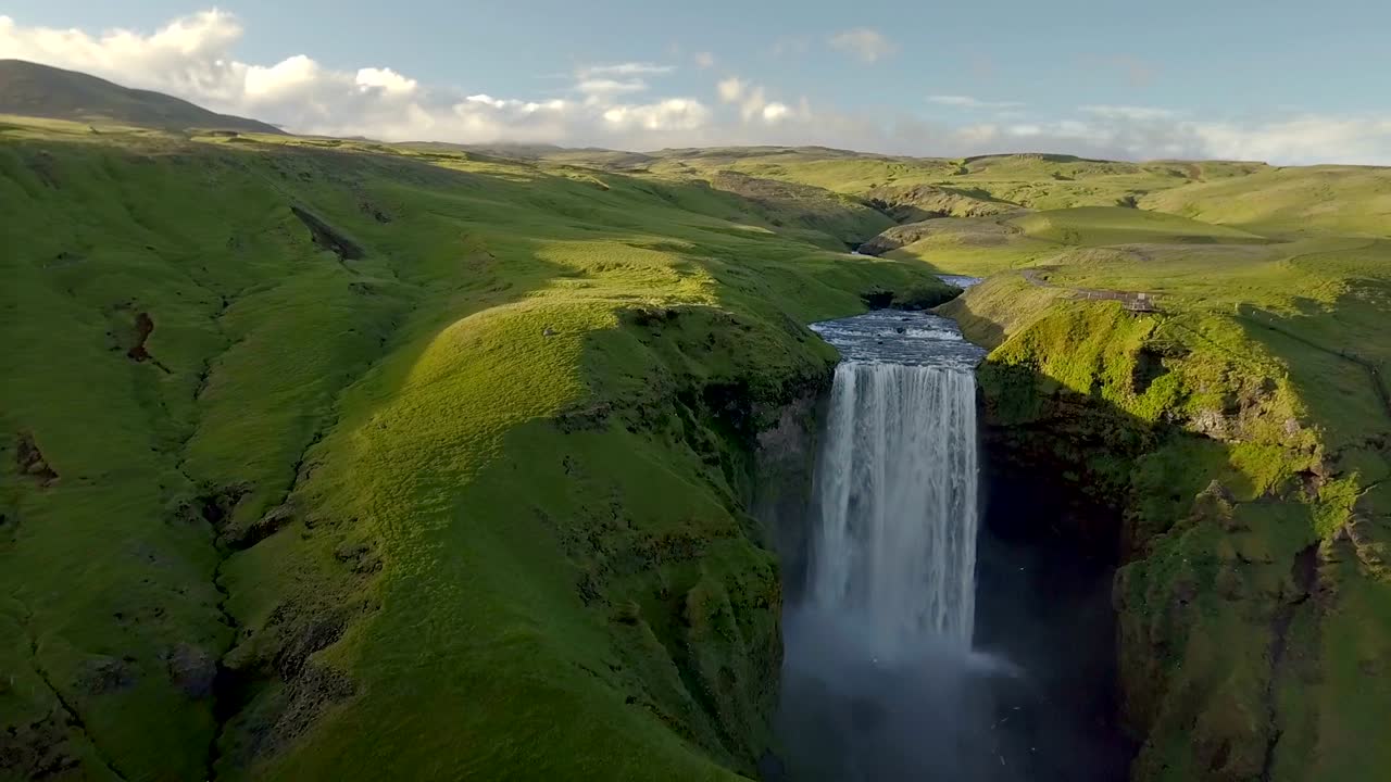 vuelo sobre la cascada de skogafoss en la naturaleza verde de islandia