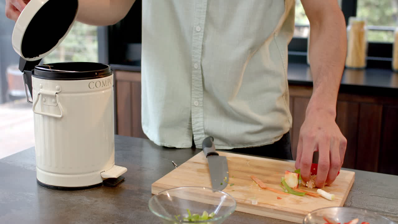 Composting vegetable scraps, man promoting eco-friendly habits in kitchen