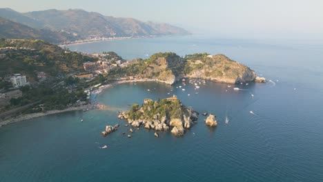 aerial boom shot above isola bella, taormina, sicily, italy