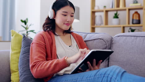 Tablet,-headphones-and-asian-woman-on-couch