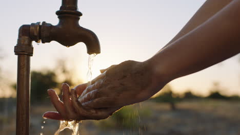 Nahaufnahme-Einer-Frau,-Die-Bei-Sonnenuntergang-Schmutzige-Hände-Unter-Leitungswasser-Mit-Frischem-Wasser-Auf-Ländlichem-Ackerland-Wäscht