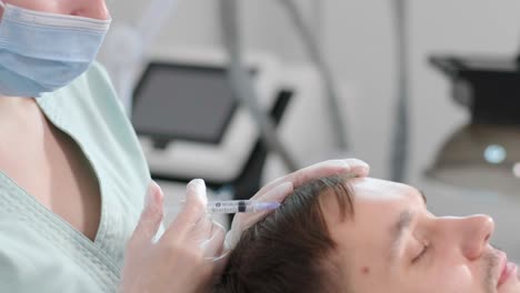 hair mesotherapy procedure in the modern cosmetology clinic. trichologist makes injections in the man’s scalp for hair growth and to prevent baldness