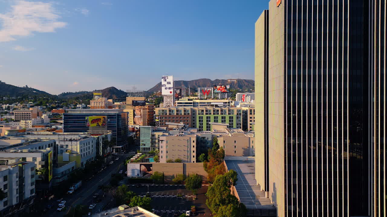 Los Angeles, USA, 29 August 2025: Footage among the facades of the high-rise buildings at daytime. Rocks with Hollywood sign at backdrop. Los Angeles, California, USA