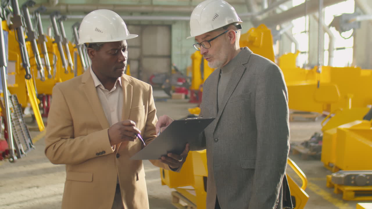 Multiethnic Managers in Hardhats Talking in Factory