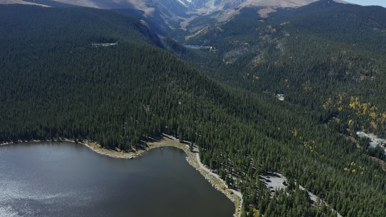 vista aérea desde el lago alpino hasta las montañas nevadas a distancia, 4k