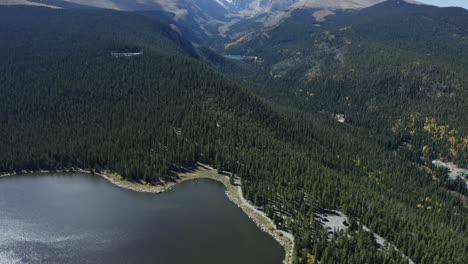 aerial view panning up from alpine lake to snowy mountains in distance, 4k