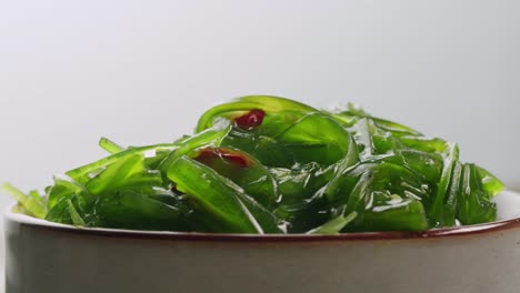 japanese wakame chuka fermented food. close-up on a detail of hiyashi wakame chuka or seaweed salad or seaweed with sesame seeds on a plate. top view. seafood background. health concept.