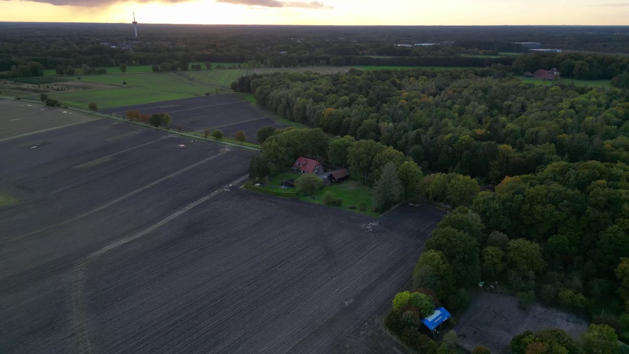 farmhouse surrounded by plowed fields, a forest, and a road in germany. Lovely aerial view flight descending drone