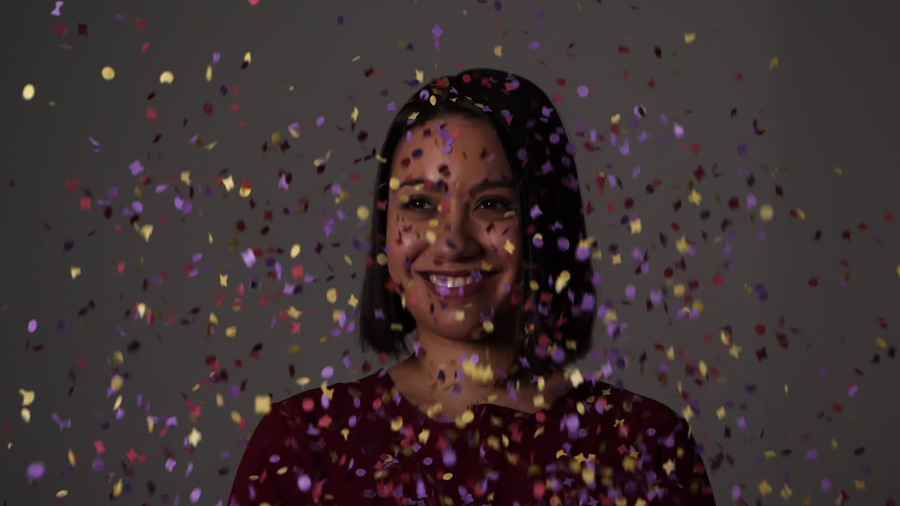 Jeune femme riante bombardée de confettis des deux côtés - Ralenti