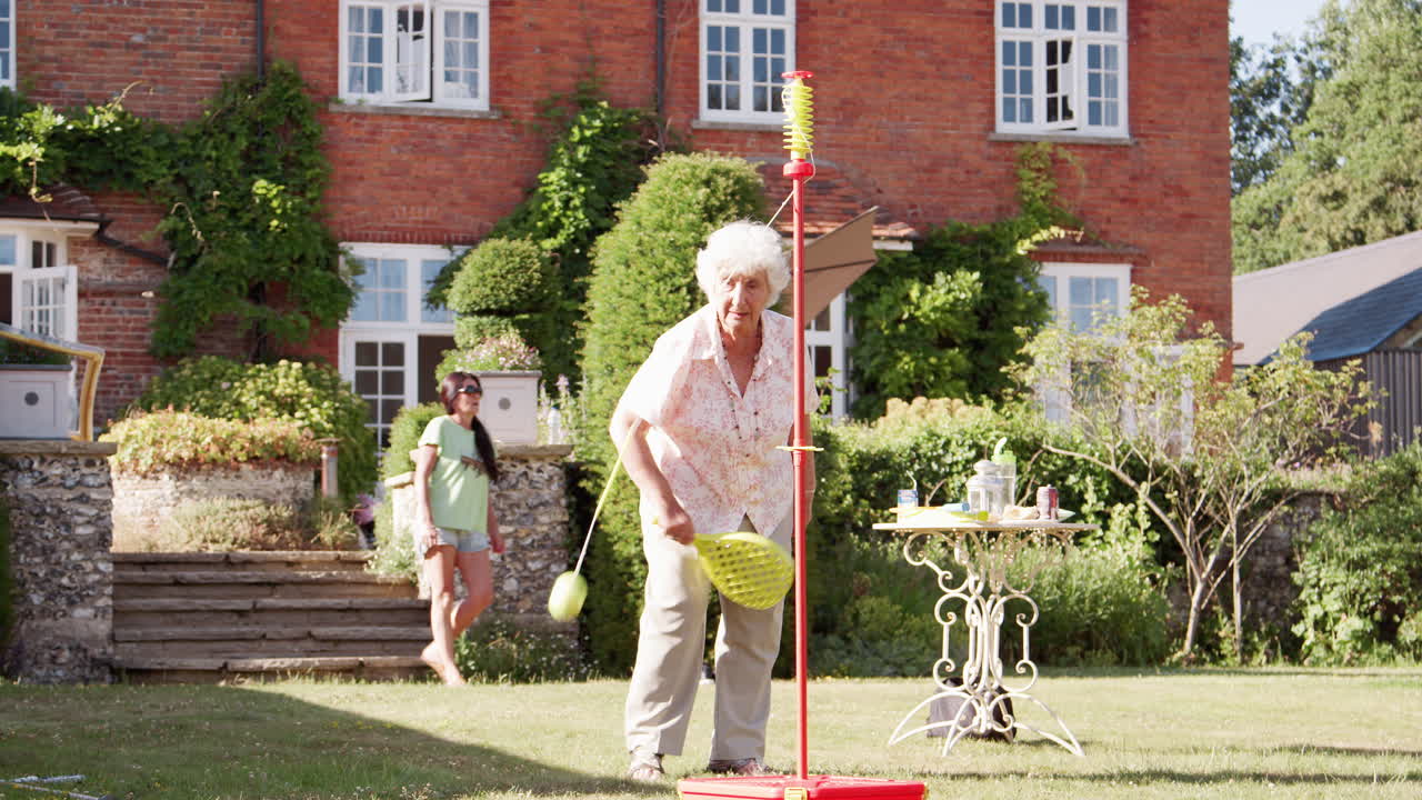 Active Senior Woman Playing Game With Bat And Ball In Garden