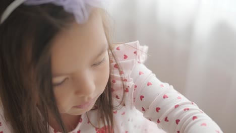 young girl sitting at a table, drawing with colorful crayons. ideal for themes of creativity, childhood development, learning, and art activities in a cozy indoor setting.