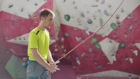 man belaying another climber on an indoor climbing wall. a man using insurance climbers holds the rope and insures his partner who climbs the mountain