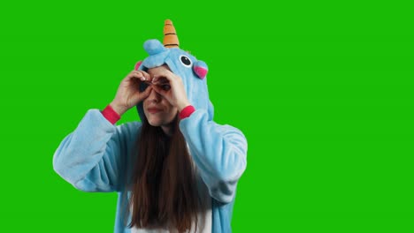 portrait of a cute young brunette girl in a beautiful unicorn costume on chrome key green background. smiling and playing. animator in costume. unicorn pajamas. 4k video with alpha channel