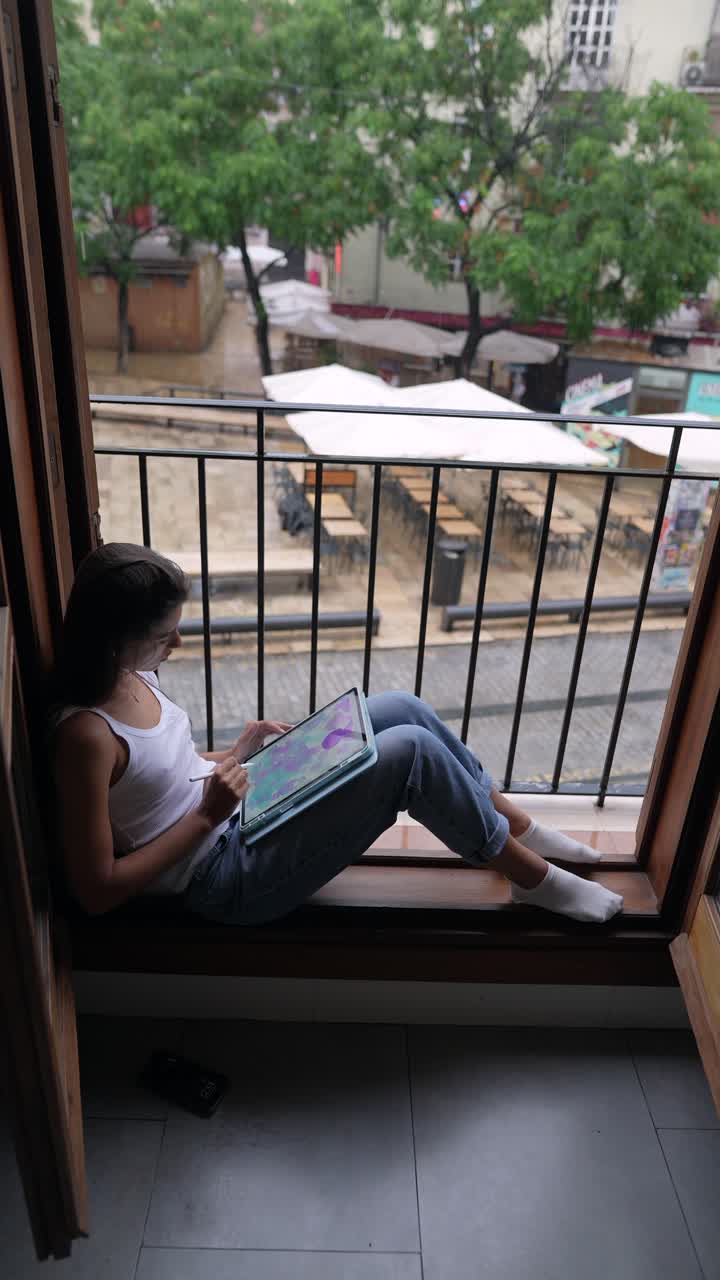 mujer trabajando en una tableta digital en el balcón