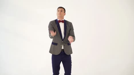 a man in a gray and blue colours of suit is juggling as a clown in the studio. parody of a funny clown in a circus