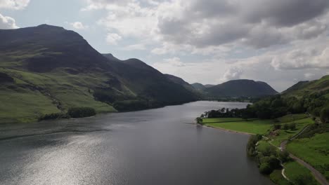 disparo de drones volando hacia atrás sobre el agua de crummock en un día soleado, lake district, cumbria, reino unido