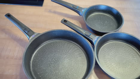 three empty non-stick frying pans