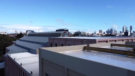 Ascending-up-to-rooftop-of-abandoned,-disused,-derelict-Art-Deco-Power-Station-Warehouse-Factory-in-East-Perth-to-skyline-view-of-Perth