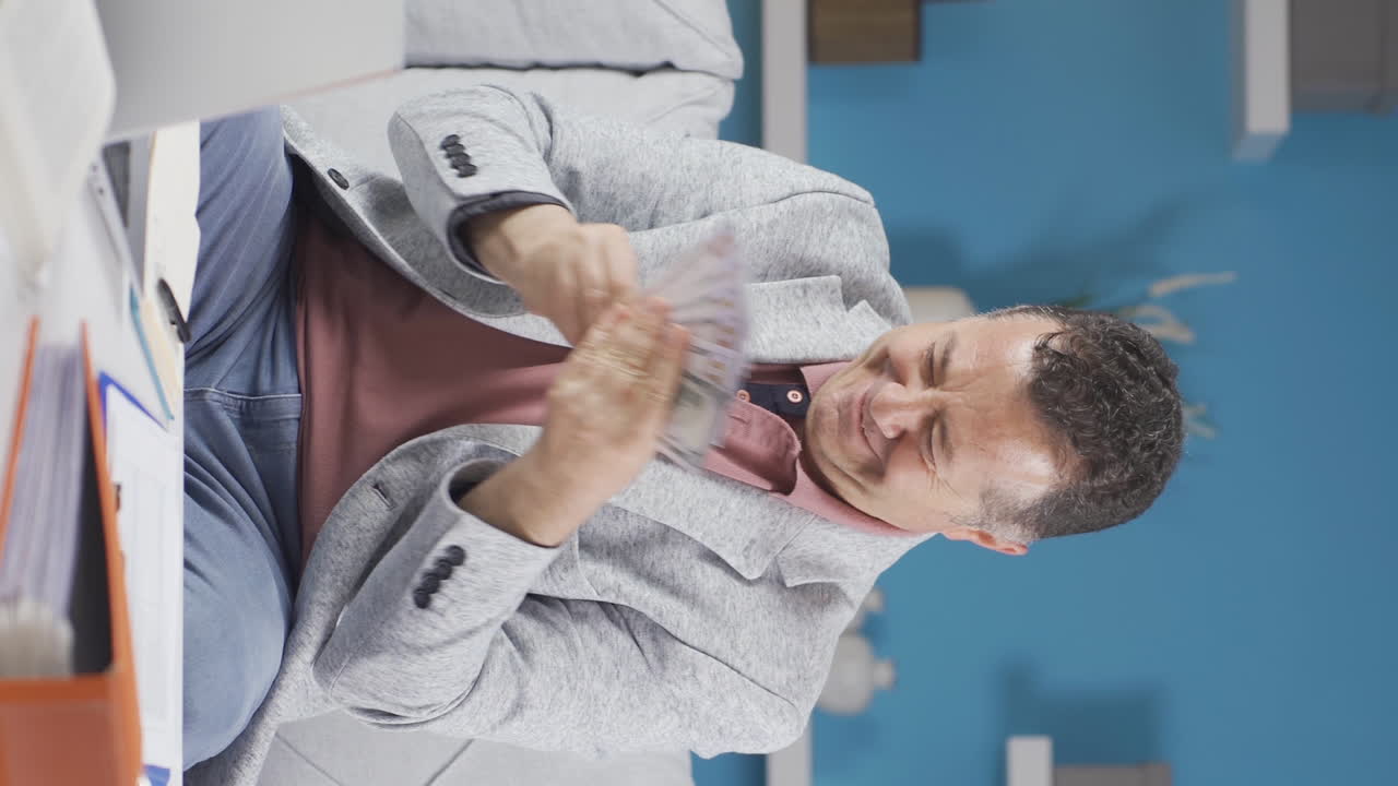 video vertical de un trabajador de oficina en casa el anciano es tacaño y ama el dinero.