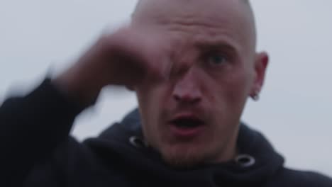 male boxer wearing a black hoodie shadowboxing against a gray sky