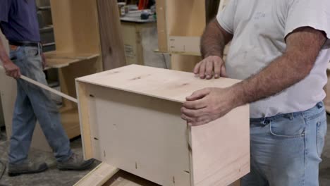 man nailing cabinet pieces together