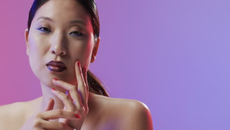 mujer asiática con cabello negro y maquillaje mirando a la cámara, copia espacio, cámara lenta