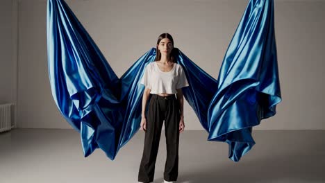 woman in white top and black pants with blue draped fabric