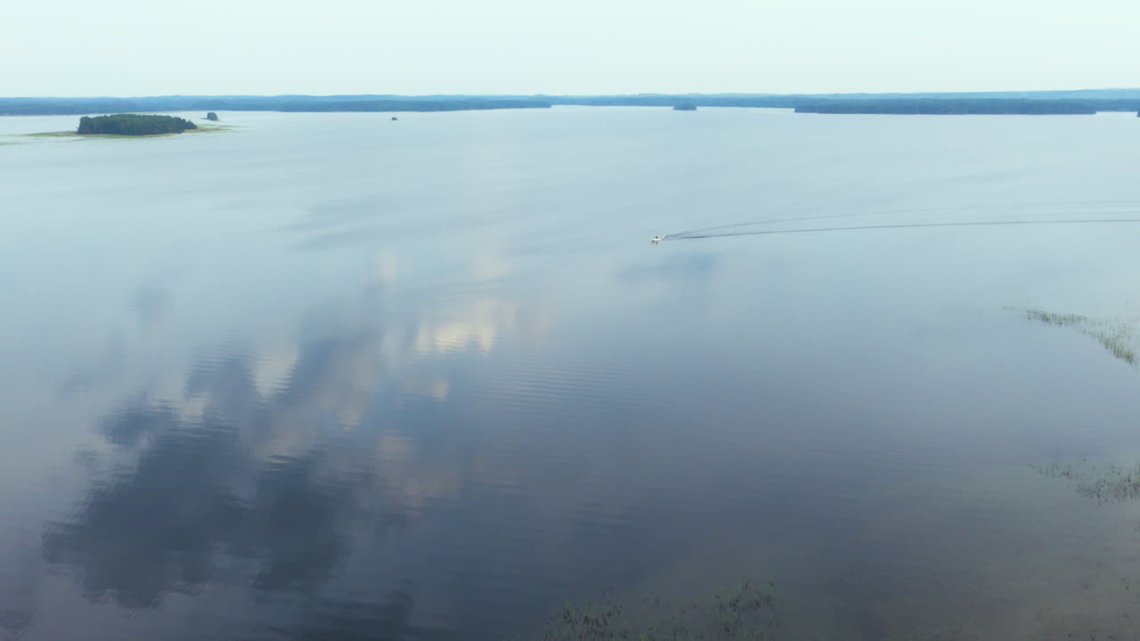 Aerial view over a island and pond, toward a boat on lake Saimaa, Finland, summer