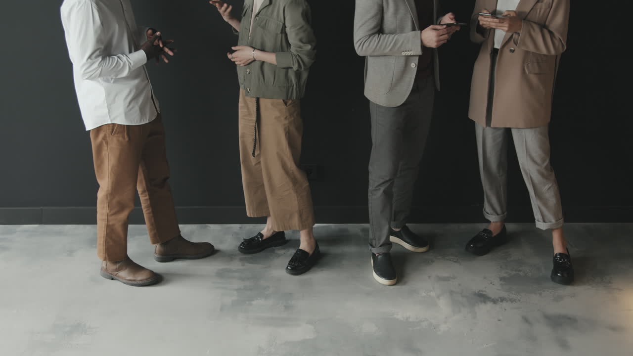 People in Smart Casual Clothes Standing against Black Wall