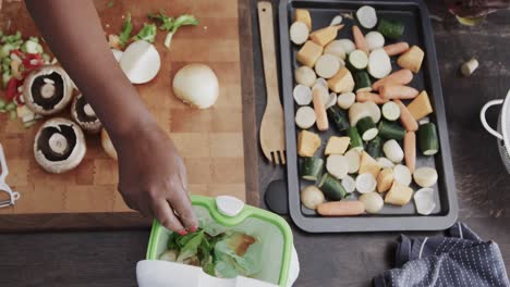 Senior-african-american-couple-throwing-food-waste-out-and-cooking-in-ktichen-in-slow-motion