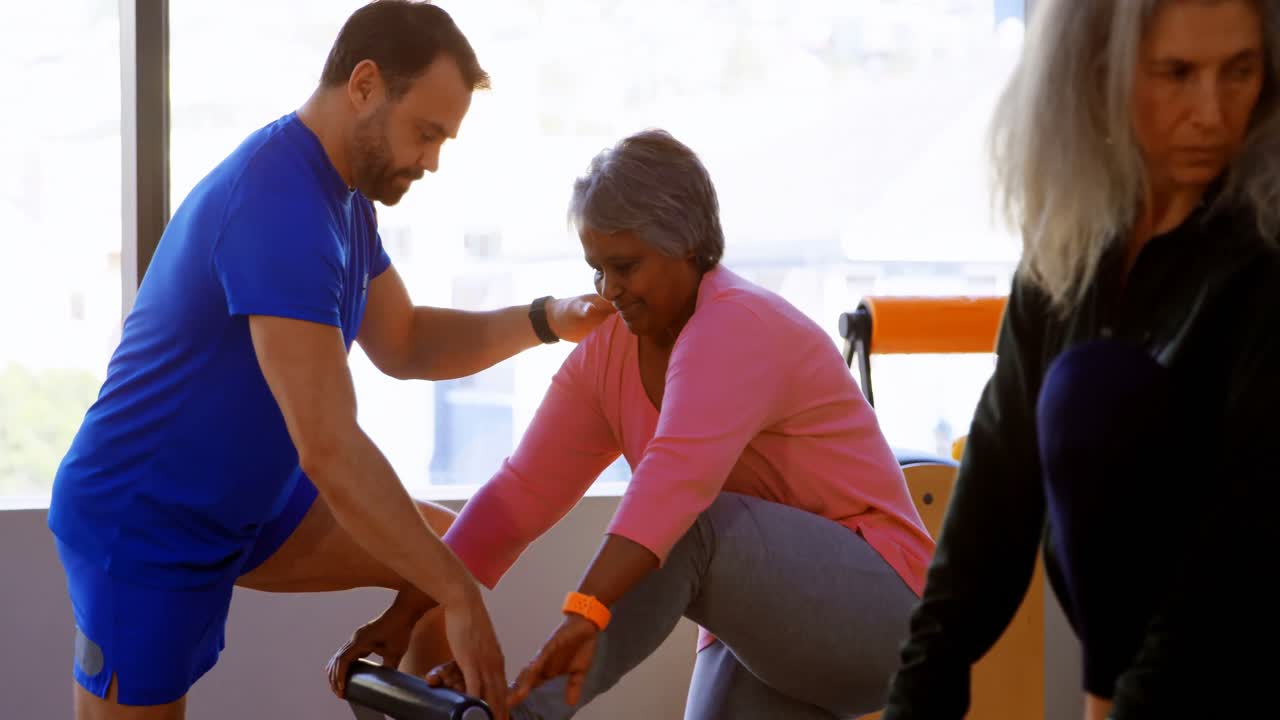 entrenador ayudando a las mujeres mayores en la realización de yoga 4k