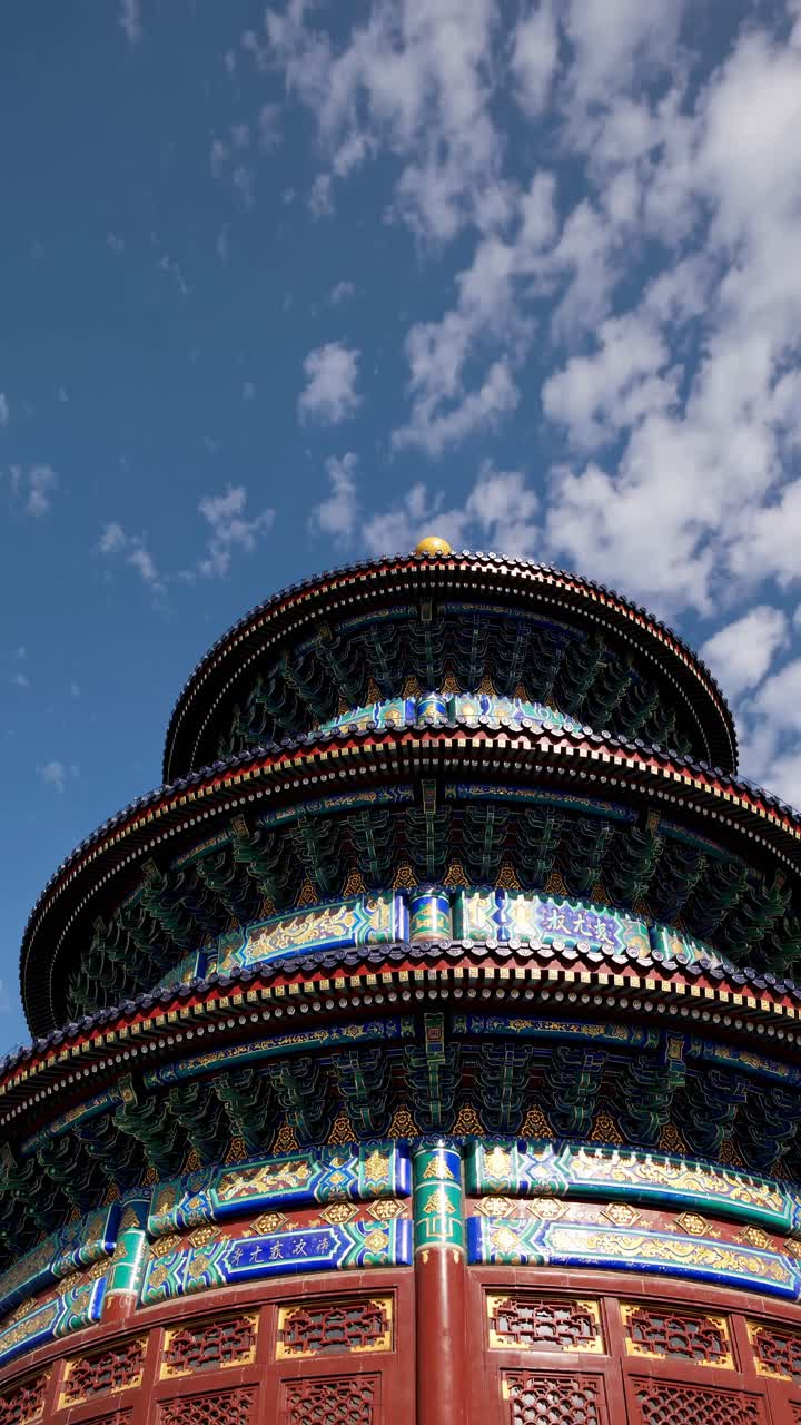 Low-angle video shot of a traditional, ornate temple roof against a blue sky with clouds