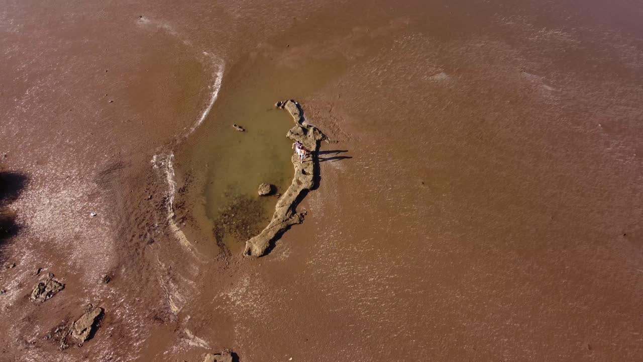 dos amigos caminando sobre rocas sobre el río de la plata, buenos aires