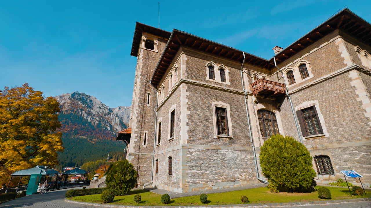 Fasade of the old brick palace at backdrop of mountains. Scenery of cozy autumn near the castle.