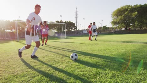 Video-of-diverse-group-of-male-football-players-on-field,-playing-football