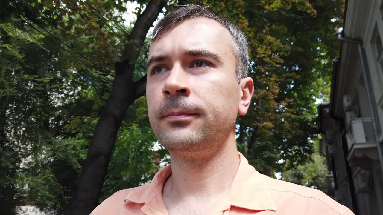 A man strolls through a lush green park on a bright sunny day. He appears thoughtful while enjoying the fresh air and natural surroundings, reflecting on various aspects of life