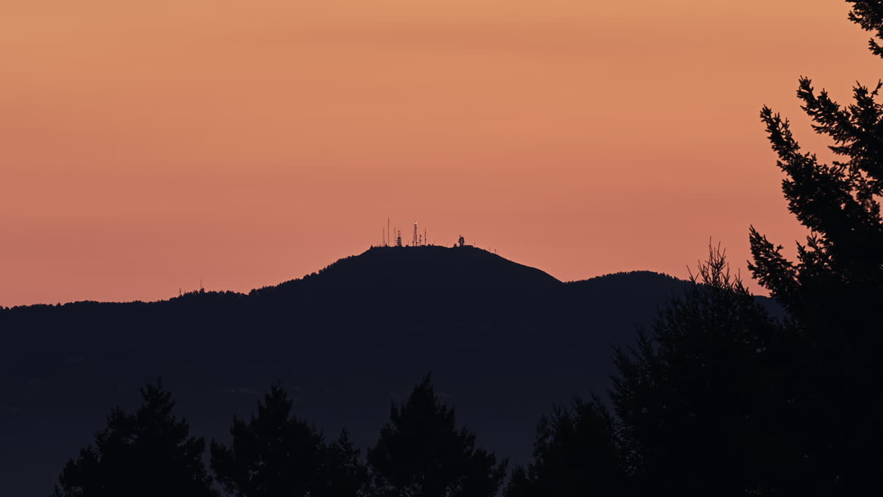 amanecer dorado con una montaña en silueta con antenas y torres de relé de microondas en el pico - lapso de tiempo