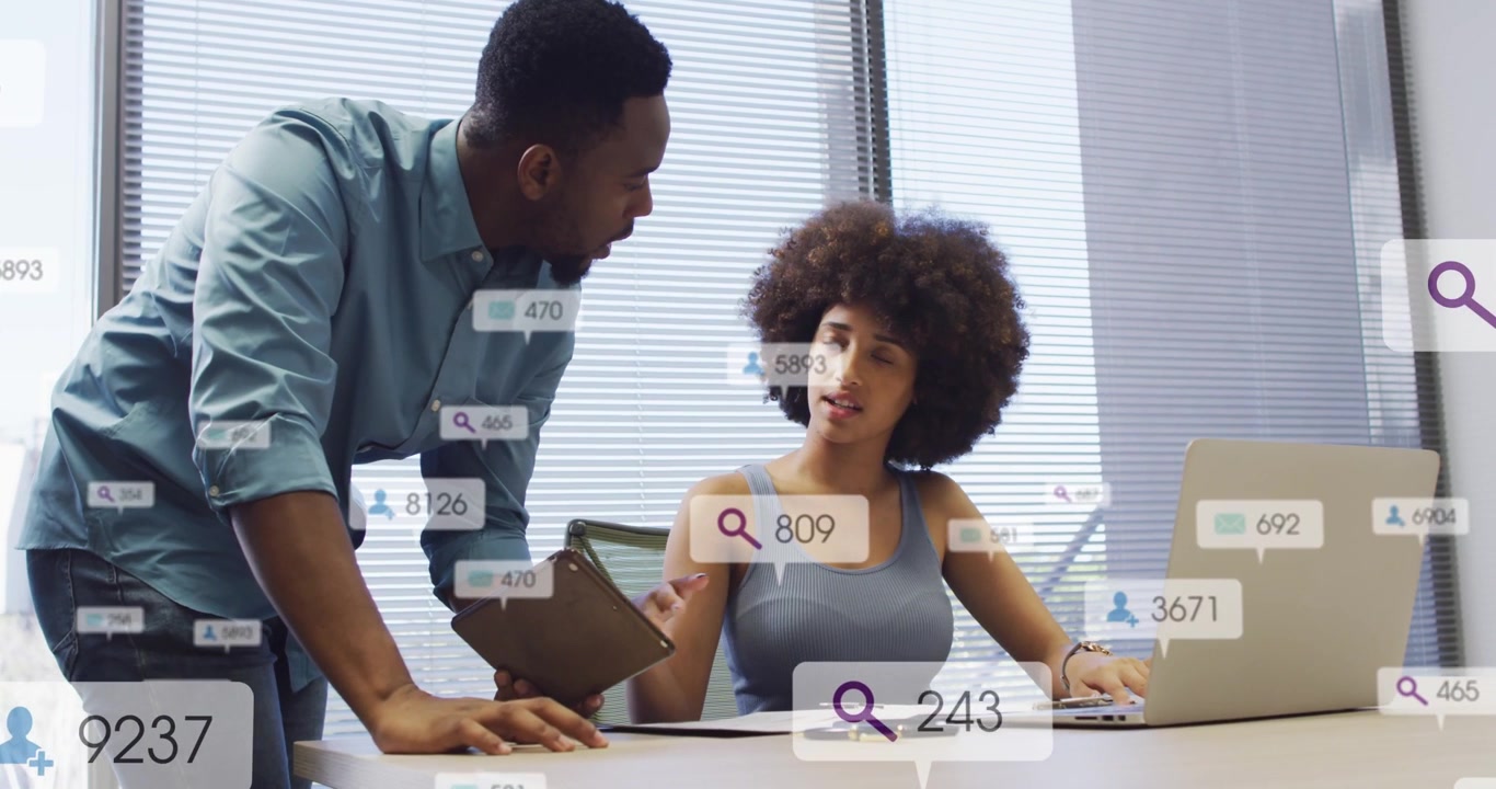 Man pointing clipboard while woman typing at laptop, UI badges appearing around laptop for business