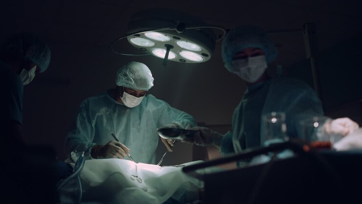 Doctors team performing surgical operation in dark hospital operating room.