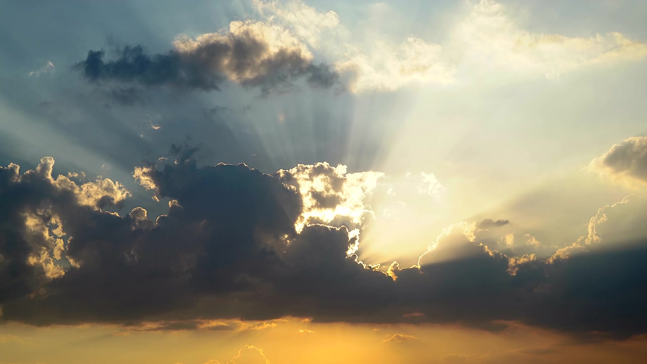 Raggi di sole dorati che filtrano attraverso nuvole temporalesche scure al tramonto