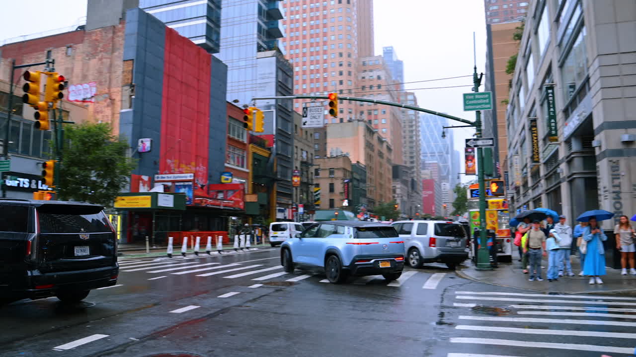 Busy streets of New York on a rainy day. Multiple people and cars on the roads and sidewalks of metropolis