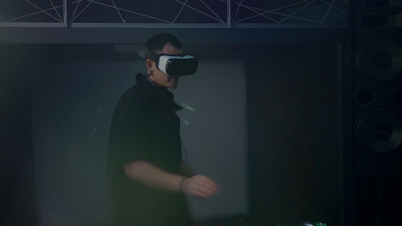 DJ in VR headset dances to music at mixing console in club