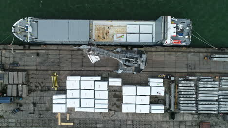 Crane-loading-a-shipping-containers-on-a-ferry---straight-down-aerial-view