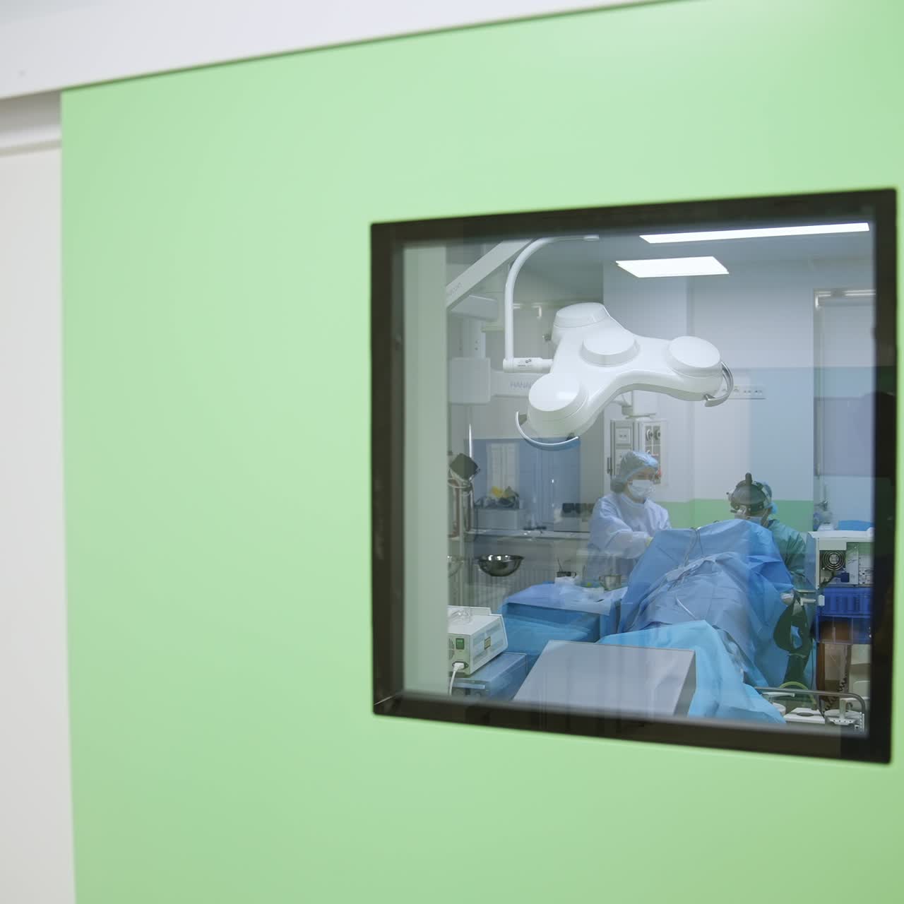 Closed doors to the surgery room in modern hospital. Medical professionals performing surgery inside the operational theatre