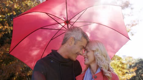 couple touching noses outdoors with umbrella