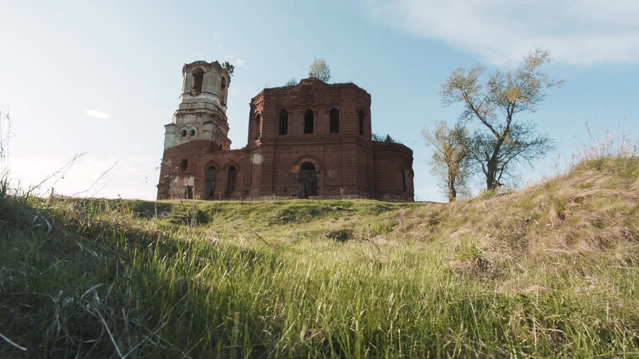 una iglesia de ladrillo en ruinas en un campo cubierto de hierba