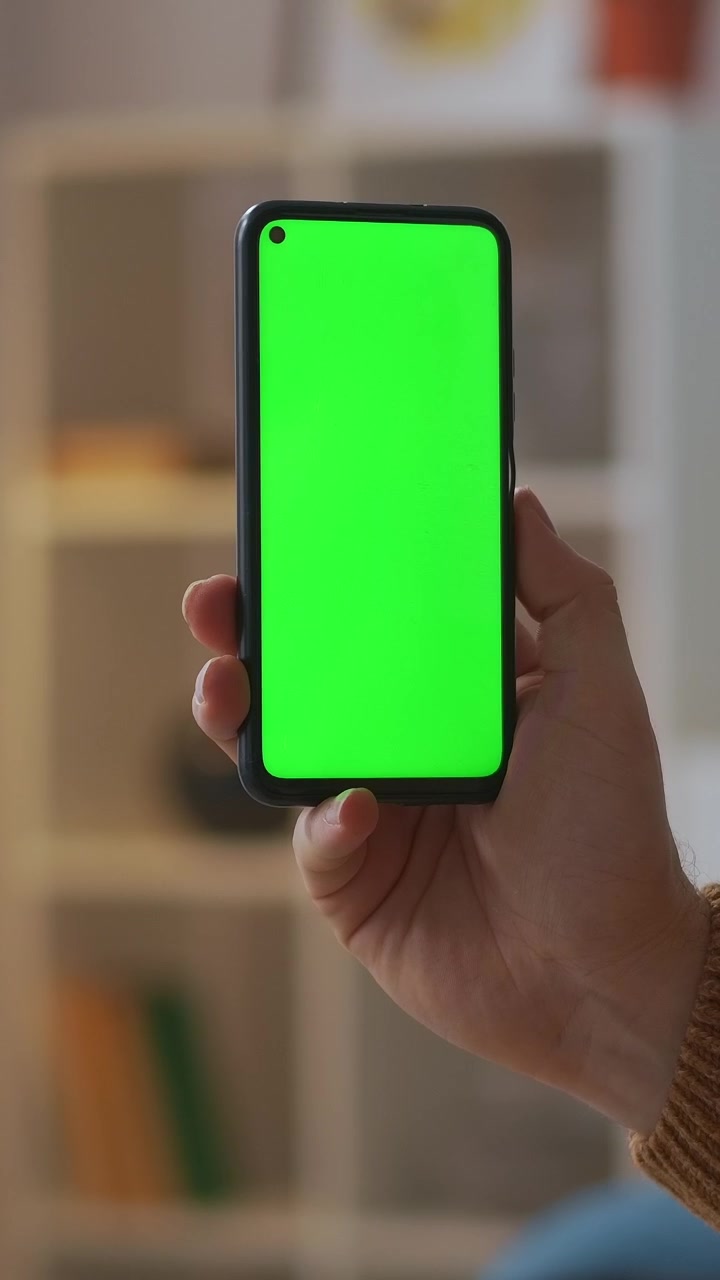 Primo piano di una mano che tiene uno smartphone in verticale con schermo verde