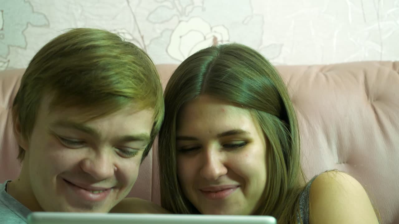 una pareja viendo algo en una tableta.