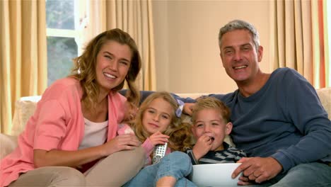 smiling family watching tv eating popcorn