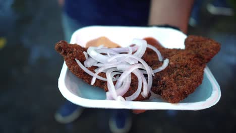 se ve a un hombre sosteniendo pescado frito, una comida bengalí popular que adoran muchos indios.